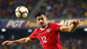 Professional footballer in Colombian national team red jersey executing precise passing technique during high-altitude match, focused intensity facial expression, well-lit stadium environment with blurred crowd background