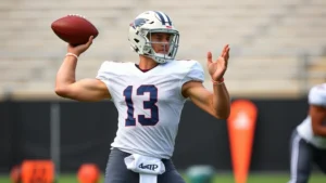 College football quarterback in perfect form during training session, showing athletic conditioning and muscle definition, throwing football with precision, outdoor practice field, dynamic motion