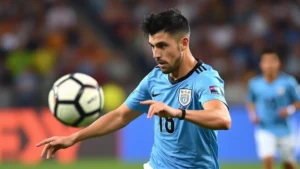 Professional footballer executing precise passing movement during high-intensity international match, wearing Uruguayan national team jersey, mid-action with focused expression and athletic positioning