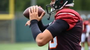 Professional quarterback wearing compression arm sleeves during practice drill, demonstrating proper fit and positioning on upper arm and forearm, athletic motion captured
