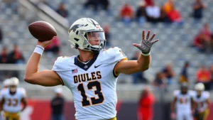 Dynamic college football player in Golden Bulls uniform executing a perfect passing technique during practice, showing athletic excellence and concentration in a stadium setting
